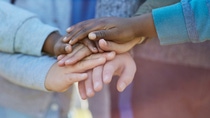 Hands of children of different skin colors lie on top of each other