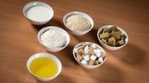 Bowls with oil, milk, flour, rice, sugar and stock cubes
