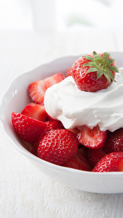 Strawberries with whipped cream in a small bowl