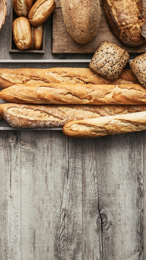 Freshly baked delicious bread on a rustic wooden worktop with copy space, healthy eating concept, flat lay